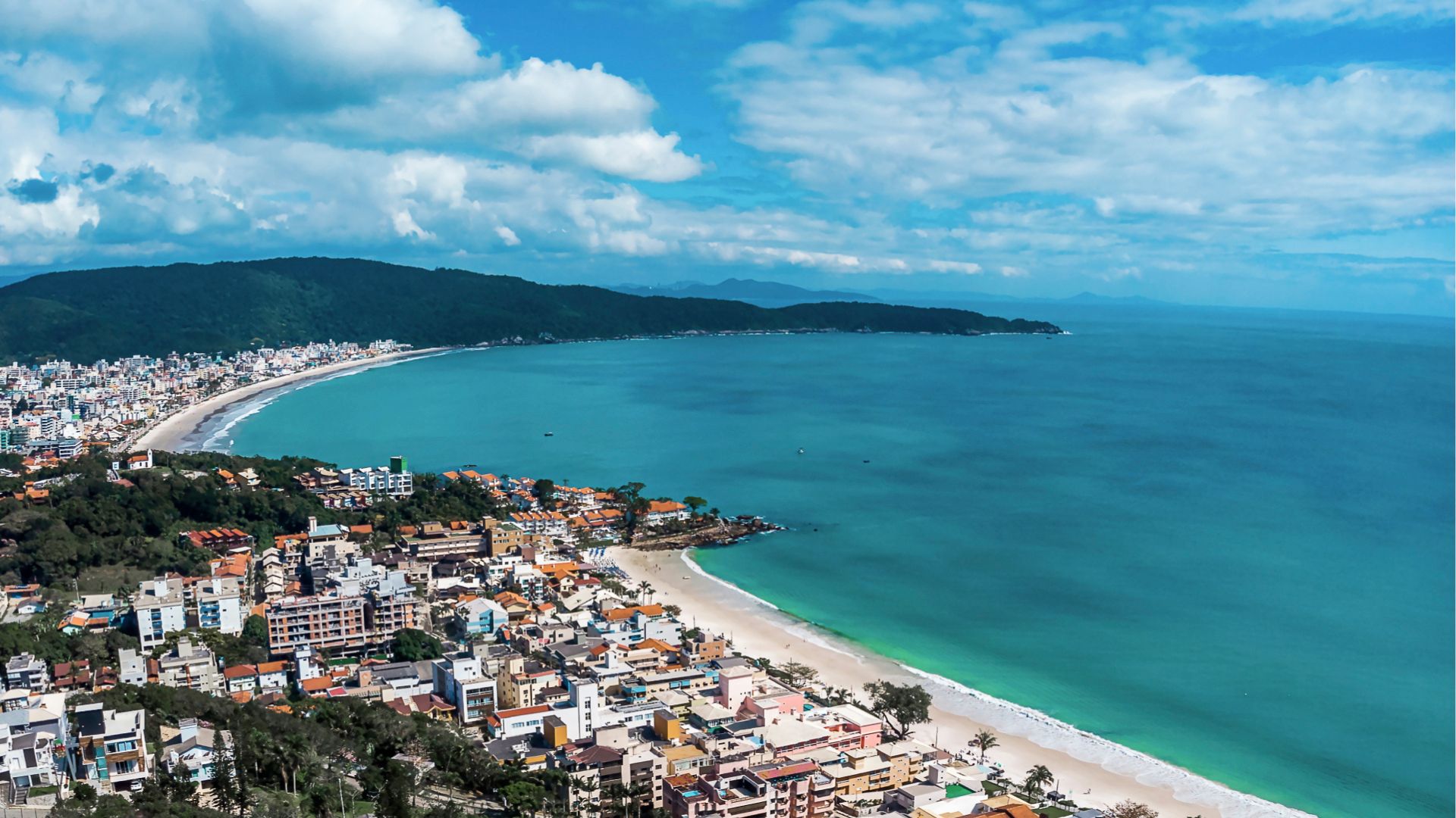 Vista panoramica de Bombinhas SC mostrando a extensao da orla e o adensamento urbano que impulsionam a valorizacao dos imoveis na regiao - Rocccoimob Imobiliária em Bombinhas