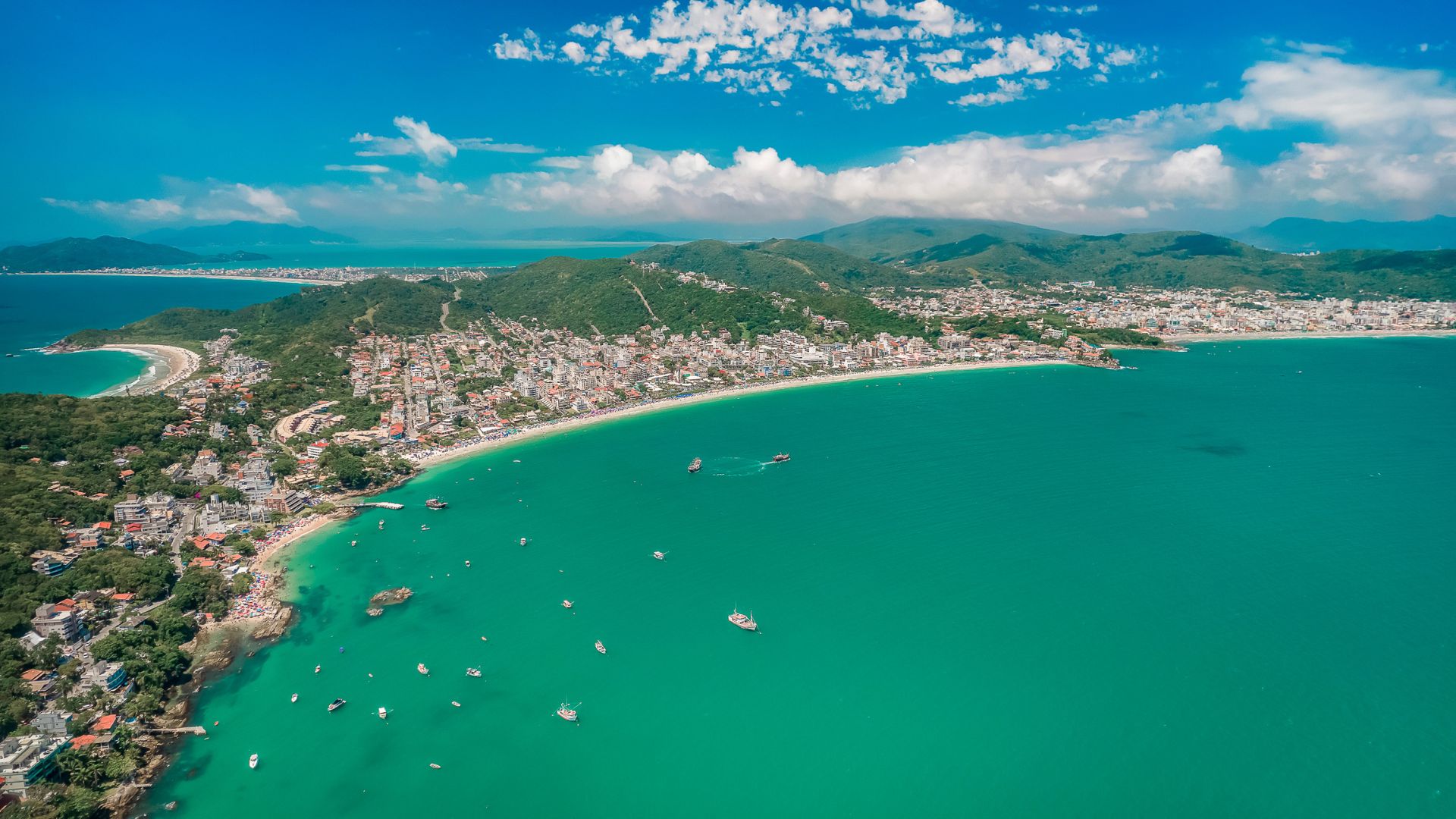 Vista panorâmica de Bombinhas, Santa Catarina, com mar verde esmeralda e imóveis à beira mar, ilustrando o potencial do mercado imobiliário local - Roccoimob Imobiliária em Bombinhas Panoramic view of Bombinhas, Santa Catarina, with emerald green sea and properties by the sea, illustrating the potential of the local real estate market - Rocccoimob Real Estate in Bombinhas