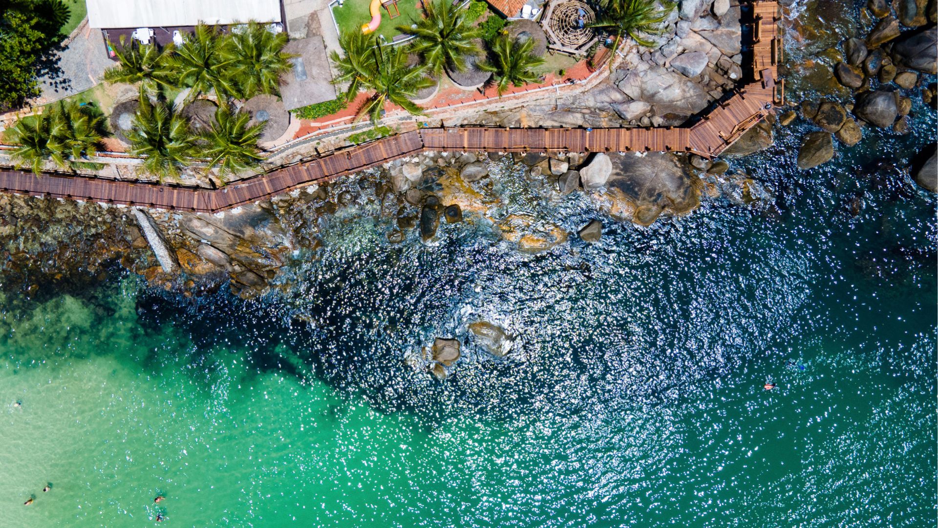 Top view of the waterfront with walkway over the rocks in Bombinhas, SC, area with direct impact on the valuation of coastal properties - Rocccoimob Real Estate in Bombinhas