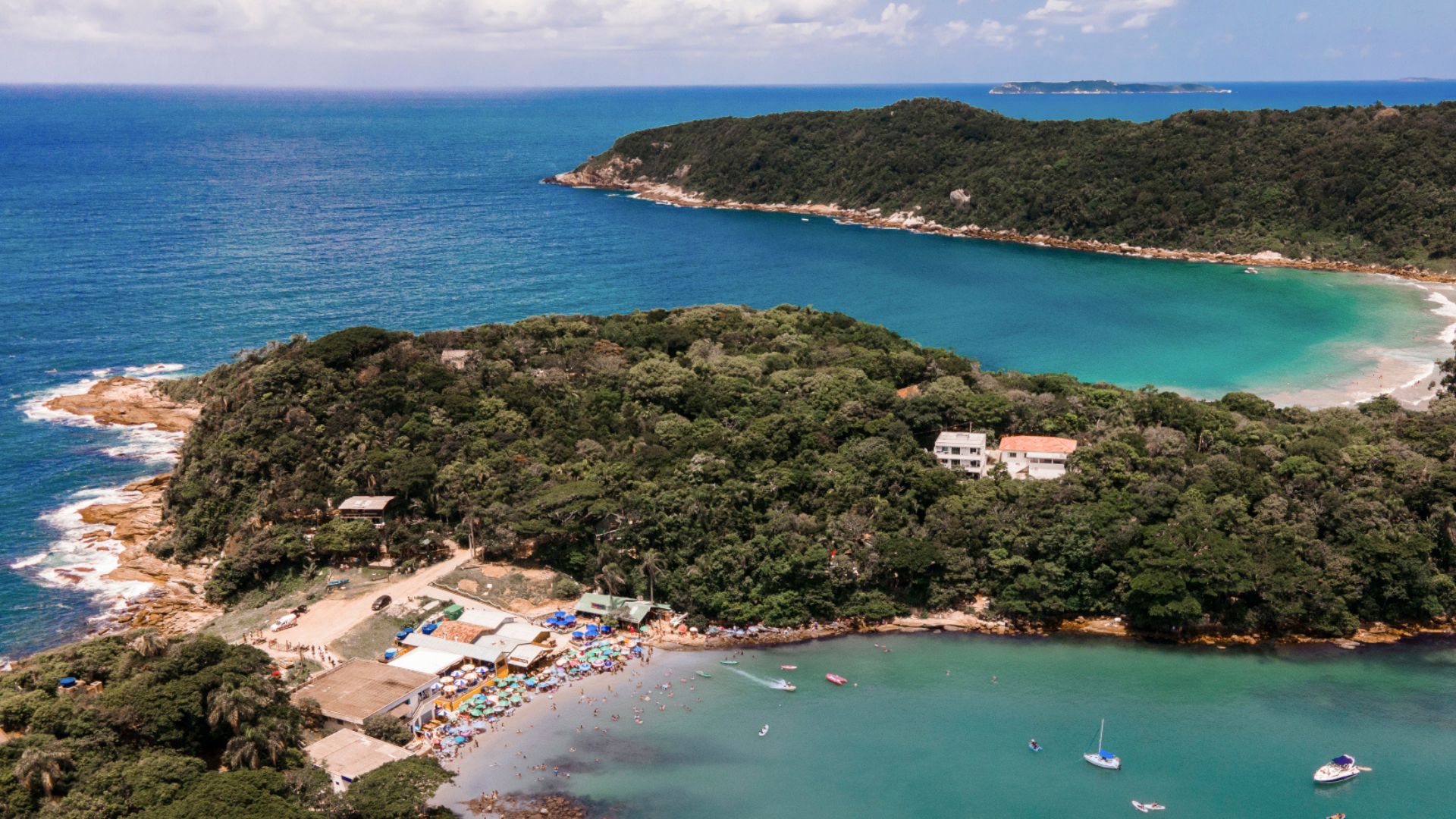 Aerial view of Praia da Sepultura in Bombinhas, Santa Catarina, with transparent sea, anchored boats and bathers enjoying the sunny day. - Rocccoimob Real Estate in Bombinhas 