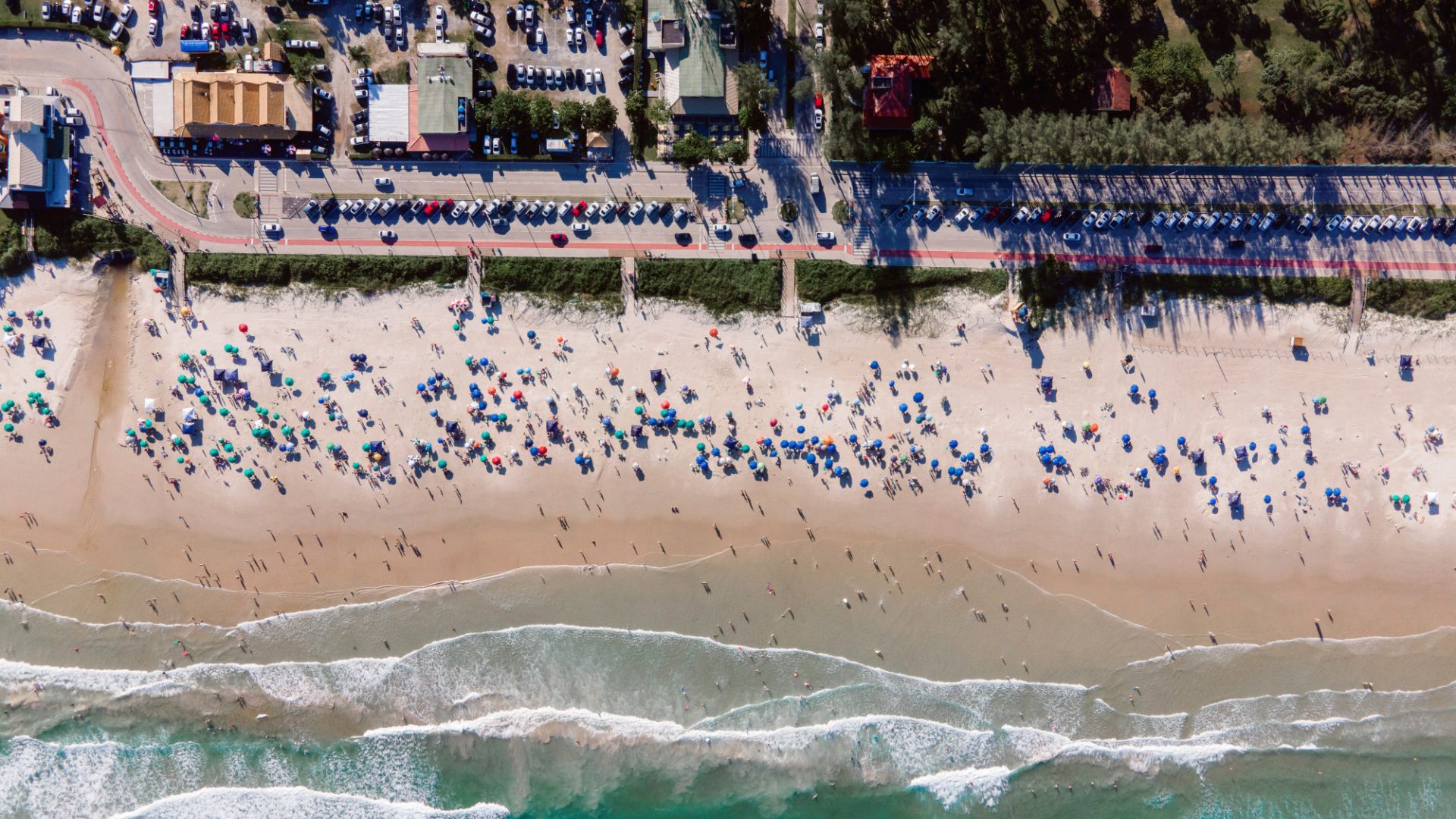 Vista aérea da praia de Mariscal, em Bombinhas, com faixa de areia larga, mar aberto e estrutura urbana organizada ao longo da orla - Rocccoimob Imobiliária em Bombinhas