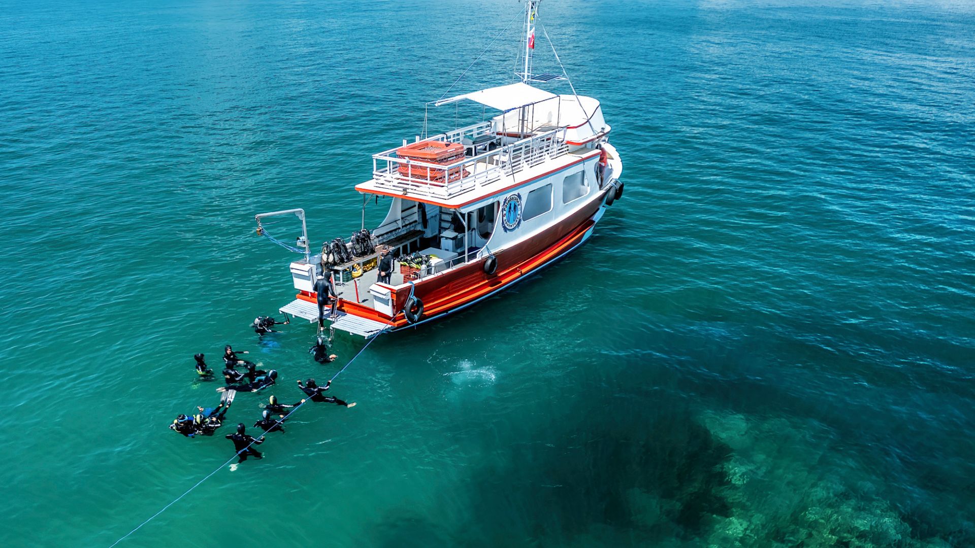 Diving boat in Bombinhas with group of tourists in the water and transparent sea seen from above - Rocccoimob Real estate in Bombinhas