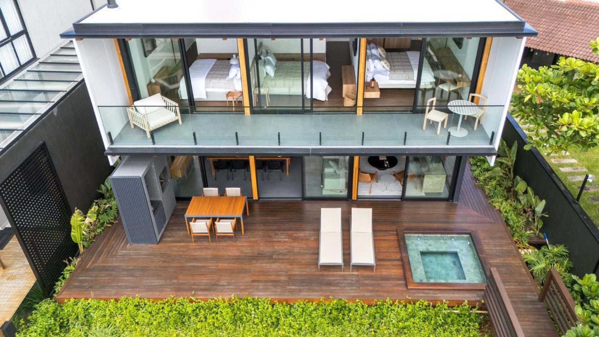 Casa de alto padrão em Mariscal vista de cima, mostrando deck amplо com hidromassagem, área gourmet integrada e suítes com sacada voltada para o verde - Rocccoimob Imobiliária em Bombinhas