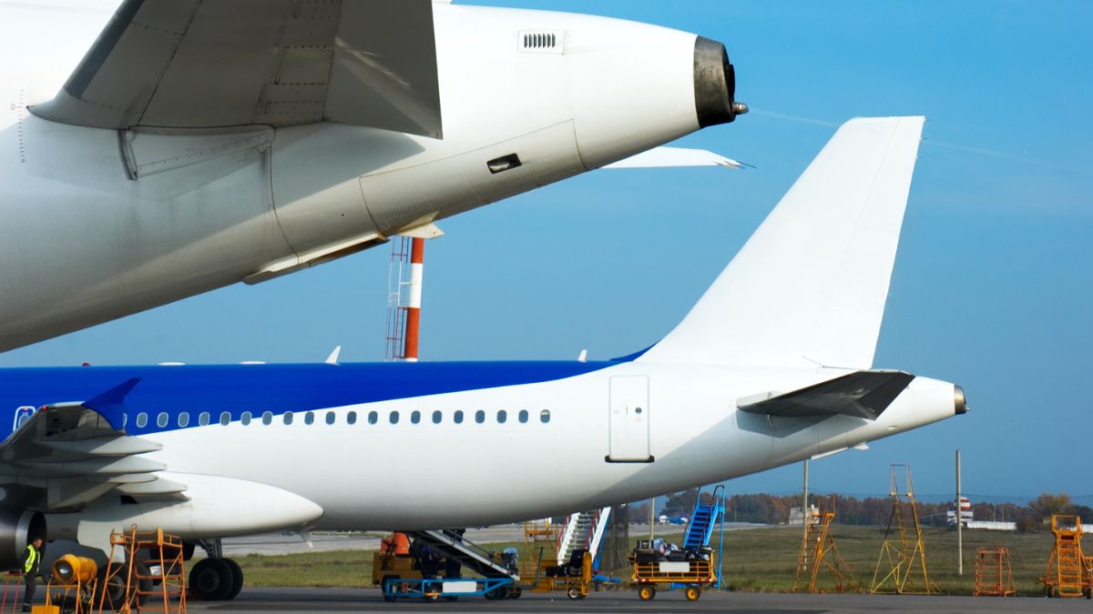 Avión en la zona de mantenimiento del aeropuerto, con equipo terrestre y otra aeronave en el fondo - Rocccoimob Real Estate en Bombinhas