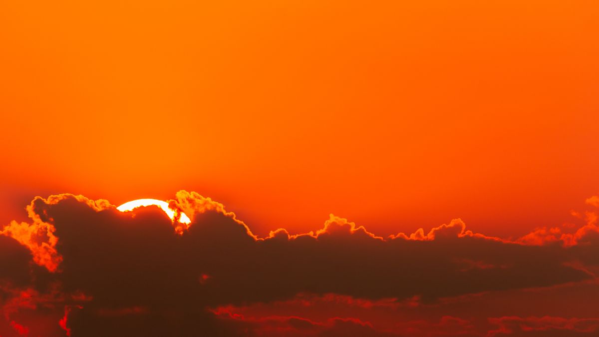 Cielo rojo intenso en Australia durante un fenómeno meteorológico, con el sol parcialmente cubierto por nubes y una atmósfera cargada de partículas. - Inmobiliaria Rocccoimob en Bombinhas