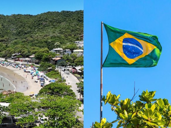 Praia movimentada com guarda sóis coloridos e vegetação ao redor em Bombinhas, ao lado da bandeira do Brasil hasteada contra o céu azul - Rocccoimob Imobiliária em Bombinhas