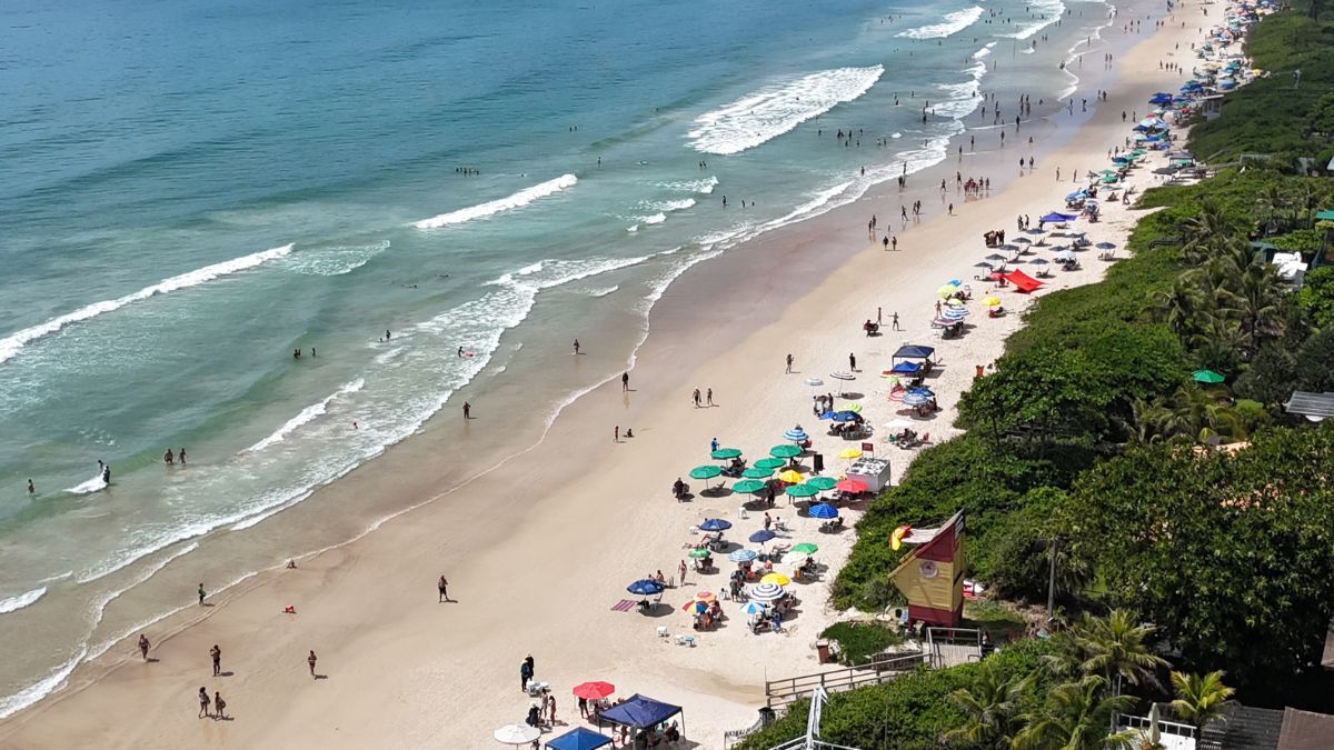 Vista aérea de Canto Grande, com faixa de areia extensa, mar azul e movimento de banhistas, localizada próxima à Praia do Buraco Quadrado - Rocccoimob Imobiliária em Bombinhas