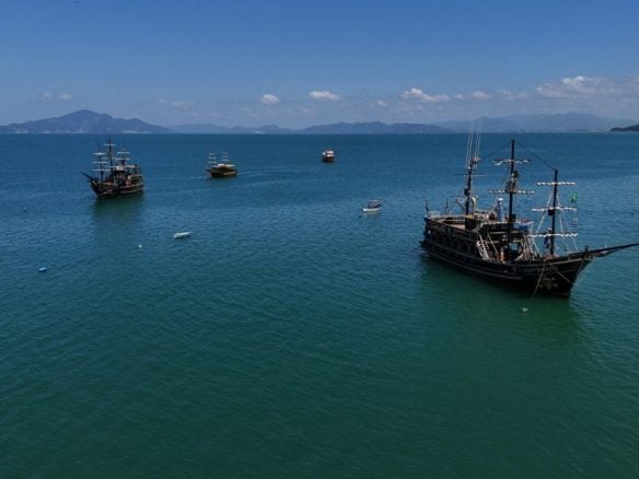 Bombinhas, cidade onde acontece a Rota da Tainha, com barcos no mar e vista panorâmica do litoral - Rocccoimob Imobiliária em Bombinhas