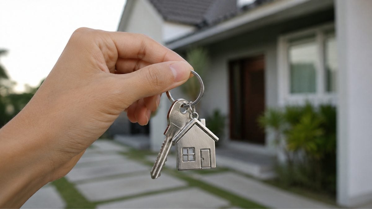 Mão segurando chave de casa em frente a um imóvel residencial, imagem relacionada ao financiamento imobiliário e compra de imóveis - Rocccoimob Imobiliária em Bombinhas