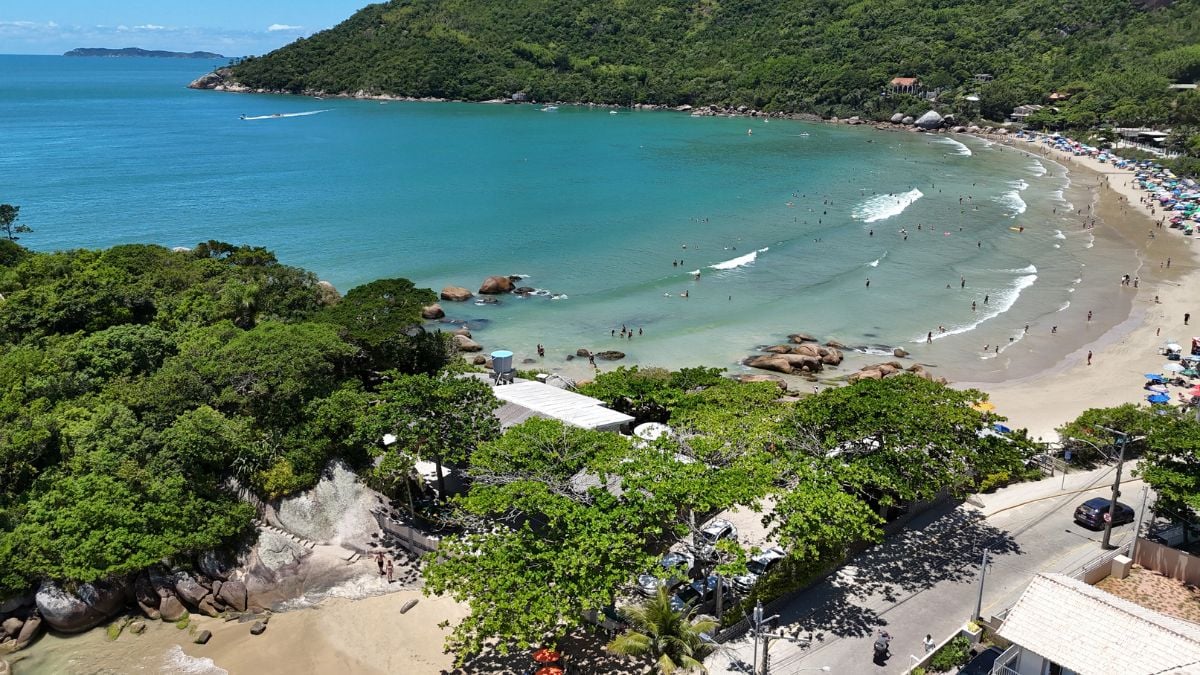 Vista aérea da Praia da Conceição, em Bombinhas, mostrando a enseada cercada por morros e costões rochosos, característica que contribui para uma maior proteção contra o vento sul - Rocccoimob Imobiliária em Bombinhas